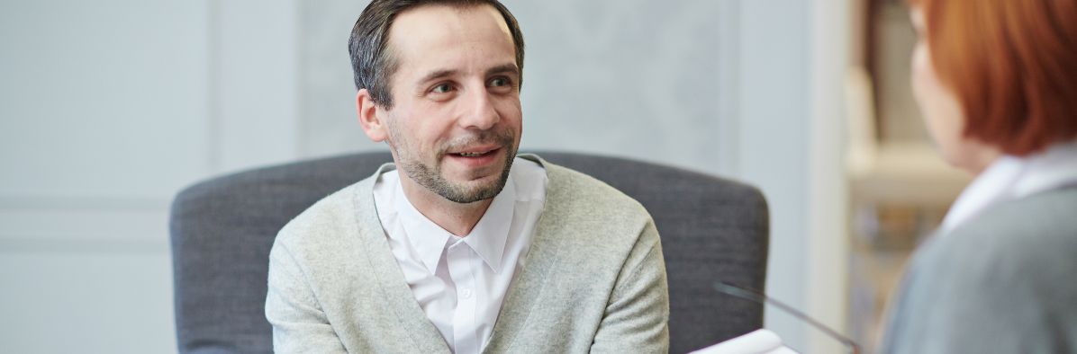 Père de famille souriant qui discute avec une travailleuse sociale.